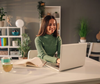 Portrait of a smiling young woman using a laptop while working at home