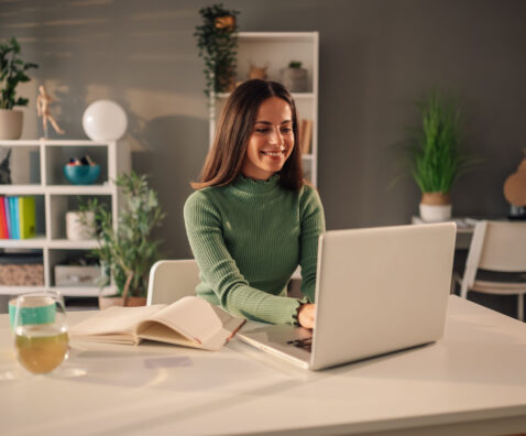 Portrait of a smiling young woman using a laptop while working at home